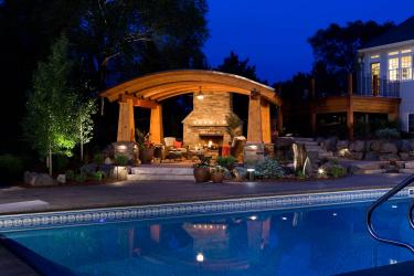 Outdoor living room, swimming pool, and elevated deck at night.