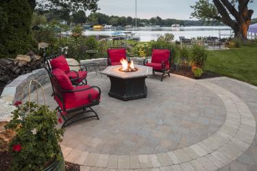Paver patio fire table circle with a stacked stone retaining wall.
