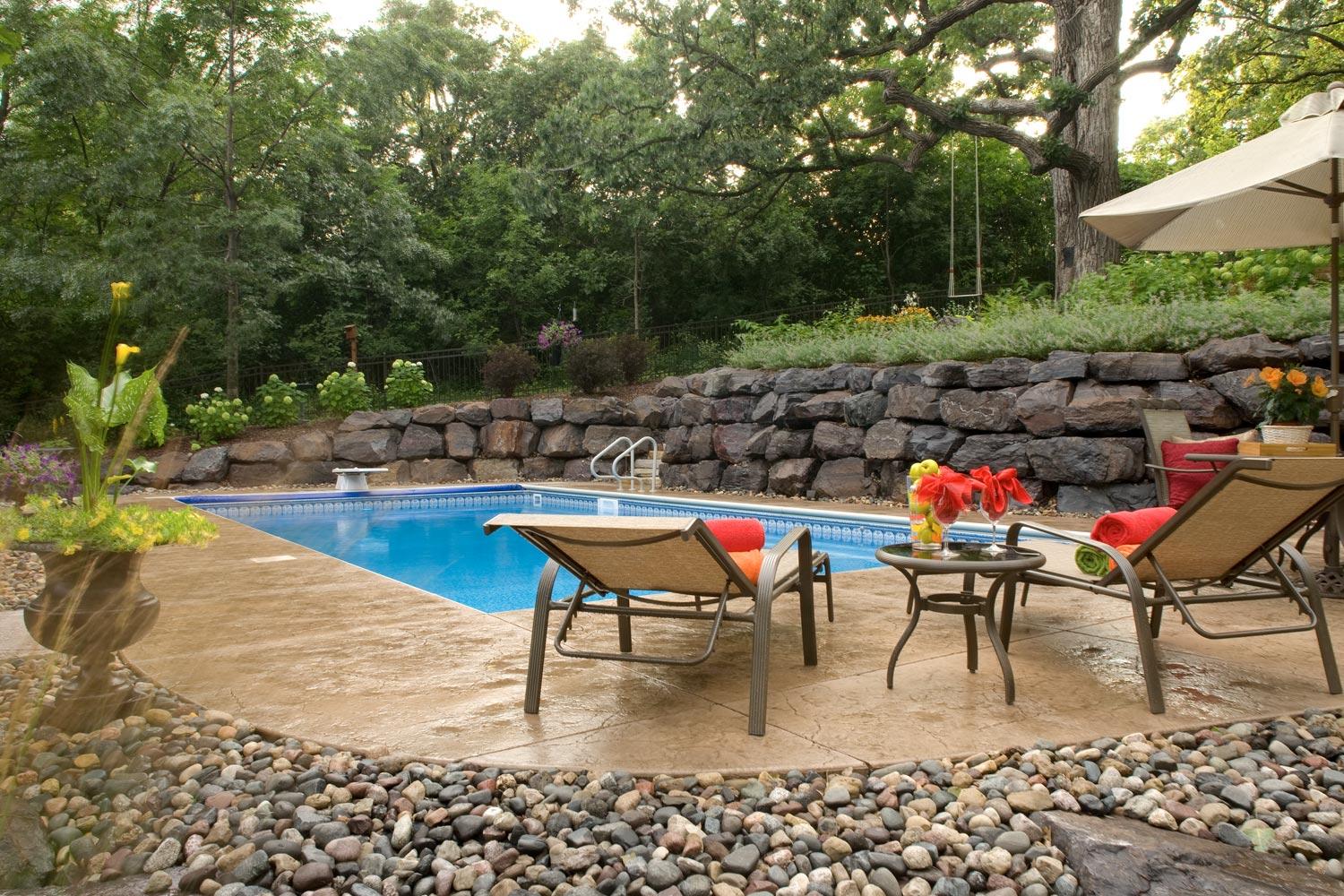 Boulder wall creates space for a swimming pool in this backyard.