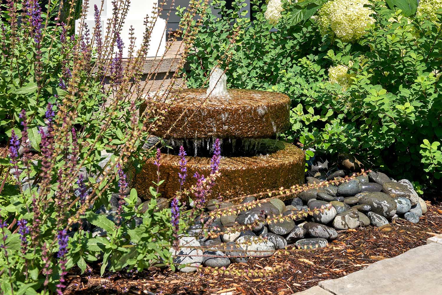 Round stacked stone water fountain in a front yard garden.