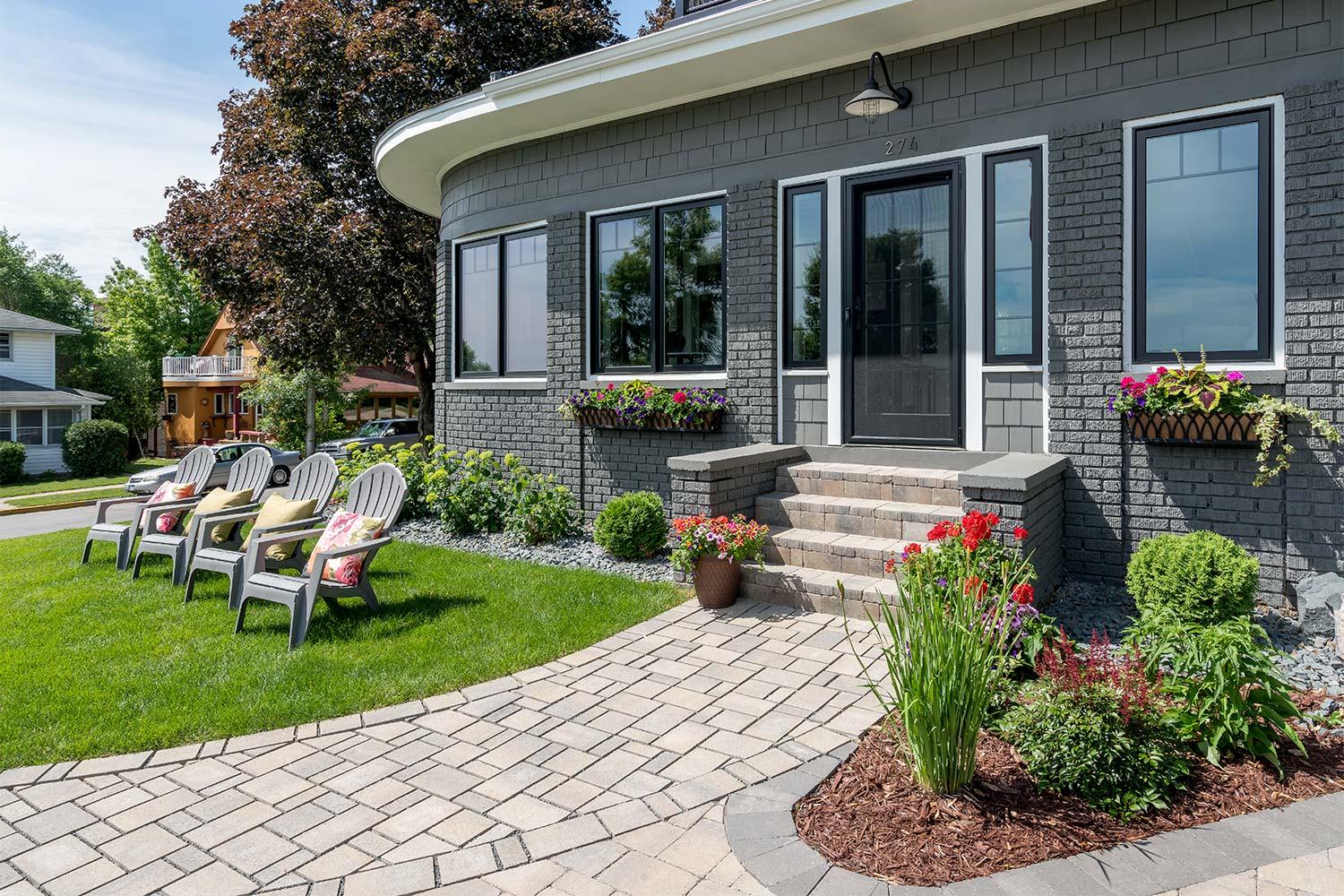 Permeable paver walkway leads to front door and steps past new lawn and four lawn chairs.
