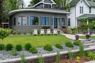 Lake Minnetonka front yard landscape design with formal garden, retaining wall, small patio and lawn with four chairs.