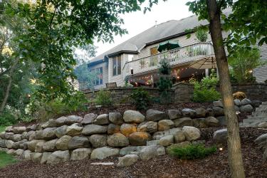 Boulder wall supports this northwoods backyard patio on a hill.