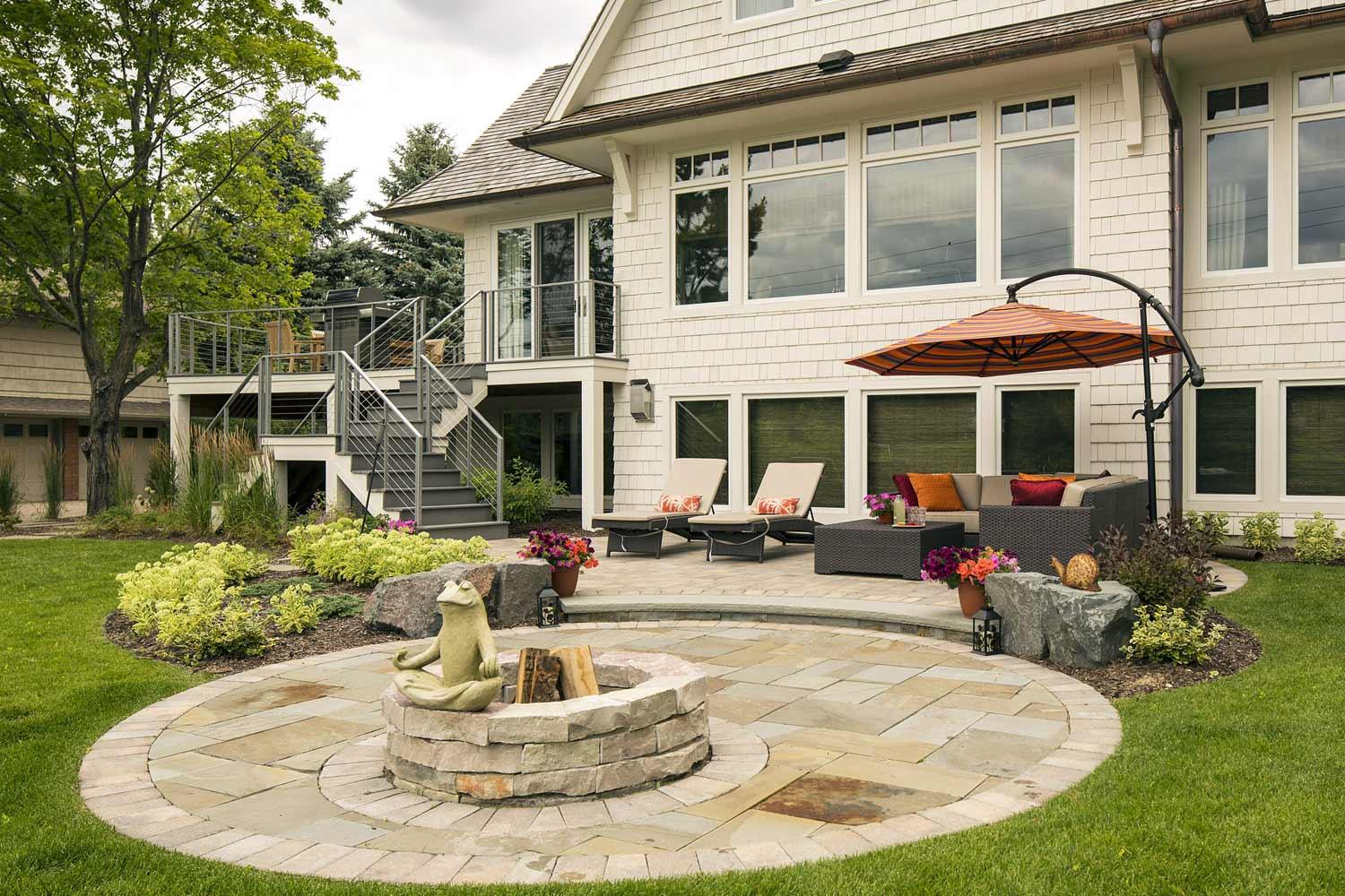 Circular backyard paver patios with a fire circle and meditating frog
