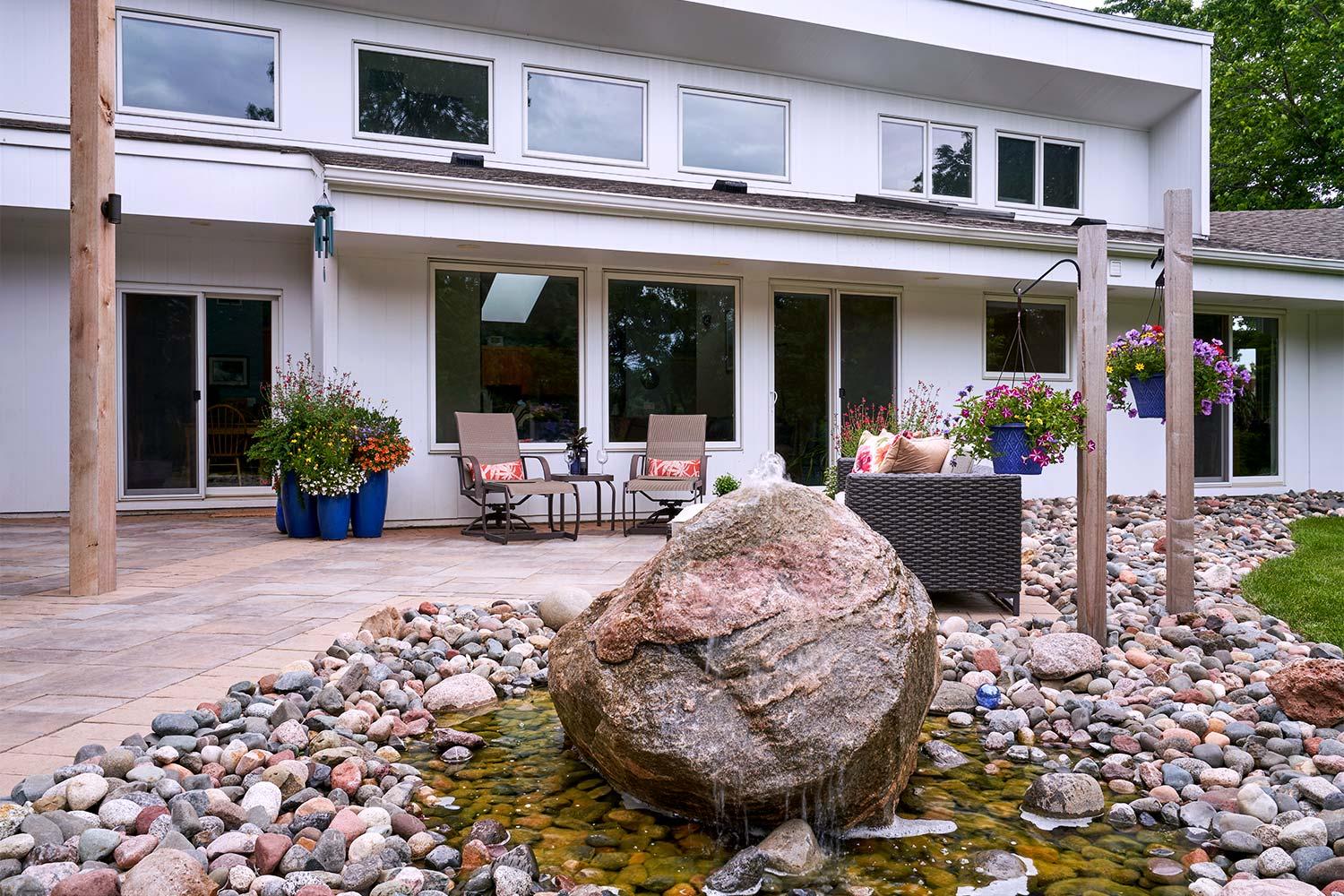 Statement water feature created from a boulder, placed in a river of stone bordering the living patio.