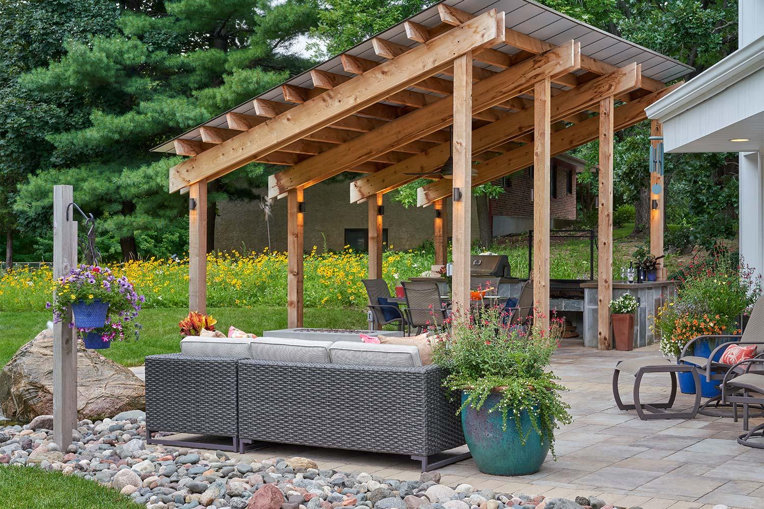 Outdoor kitchen under a modernist shade structure. Native yellow wildflowers in the background define the border between properties.