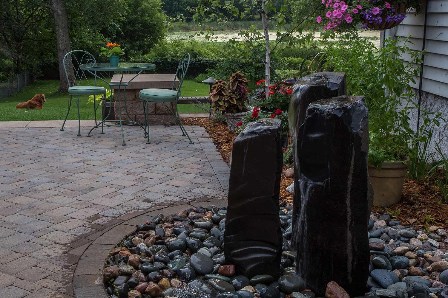 Backyard patio by a grassy lake with the basalt column water fountains.