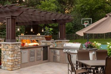 Outdoor kitchen and dining patio in a resort style backyard.