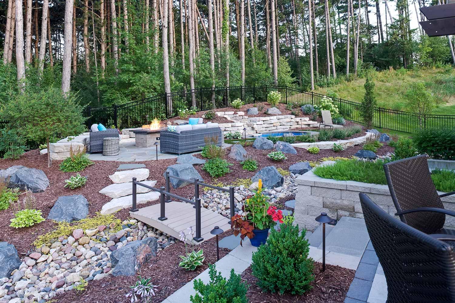 Suburban backyard with a dry stream bed, hardy plants, and no lawn.