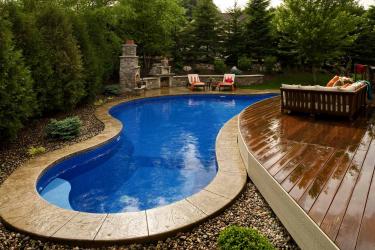 Curved backyard swimming pool fits around a deck and fire patio