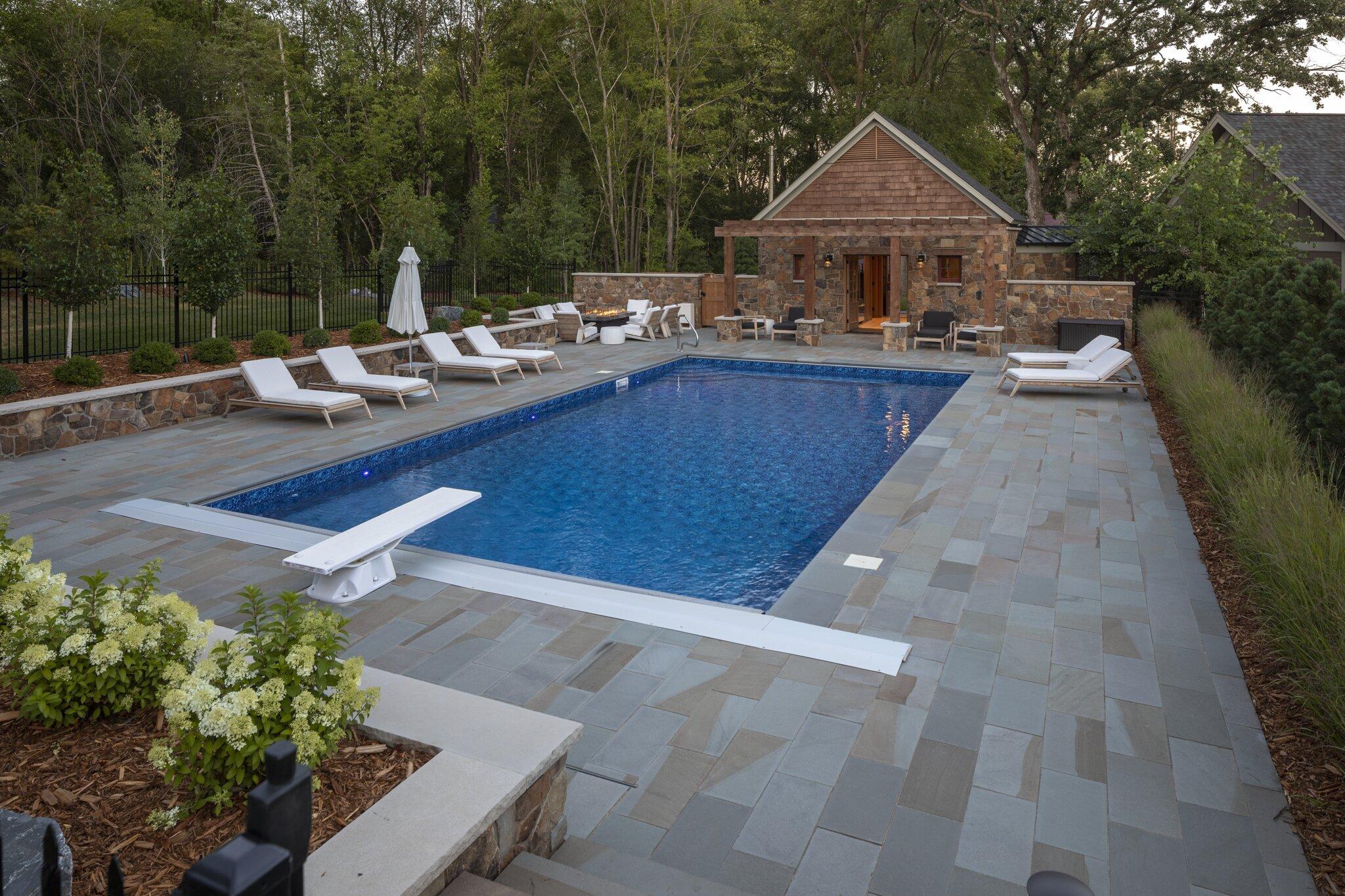 swimming pool with pool house surrounded by bluestone natural stone