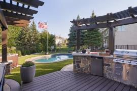 Backyard featuring a deck, outdoor kitchen, swimming pool and synthetic turf