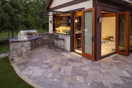 Backyard kitchen with grill, bar and natural stone patio