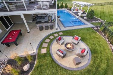 Suburban backyard with fire circle, patio, and swimming pool.