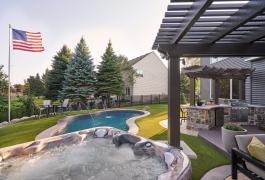 Low maintenance backyard featuring a spa, swimming pool, kitchen and synthetic turf