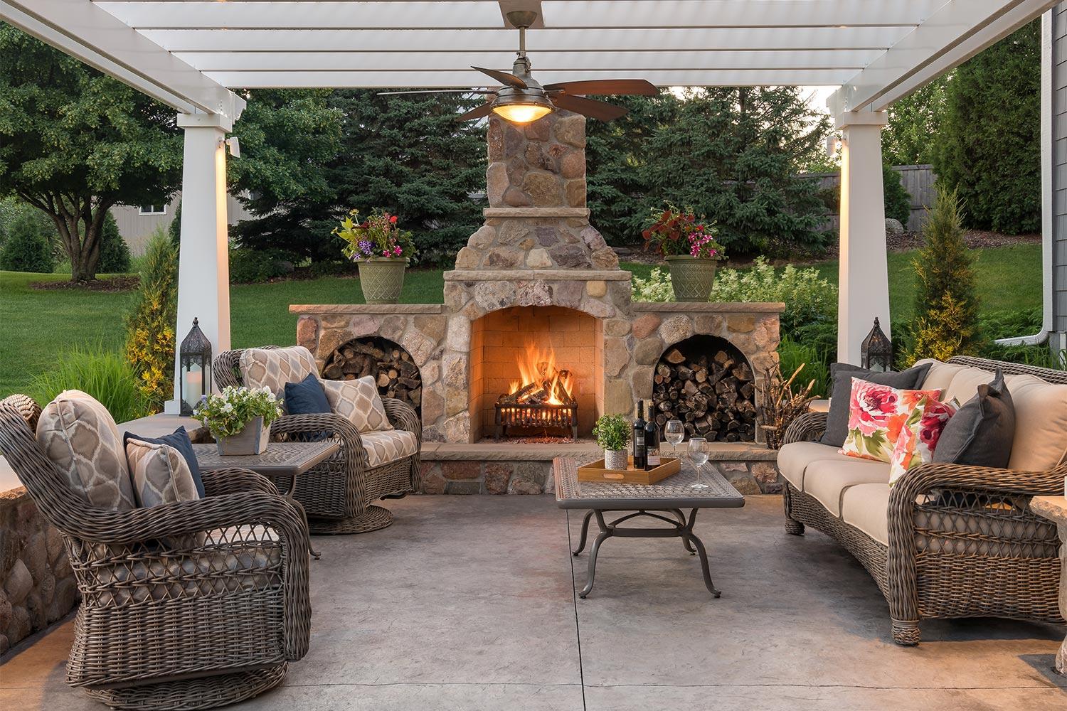 Living room patio with an oversized fireplace, ceiling fan, and pergola.