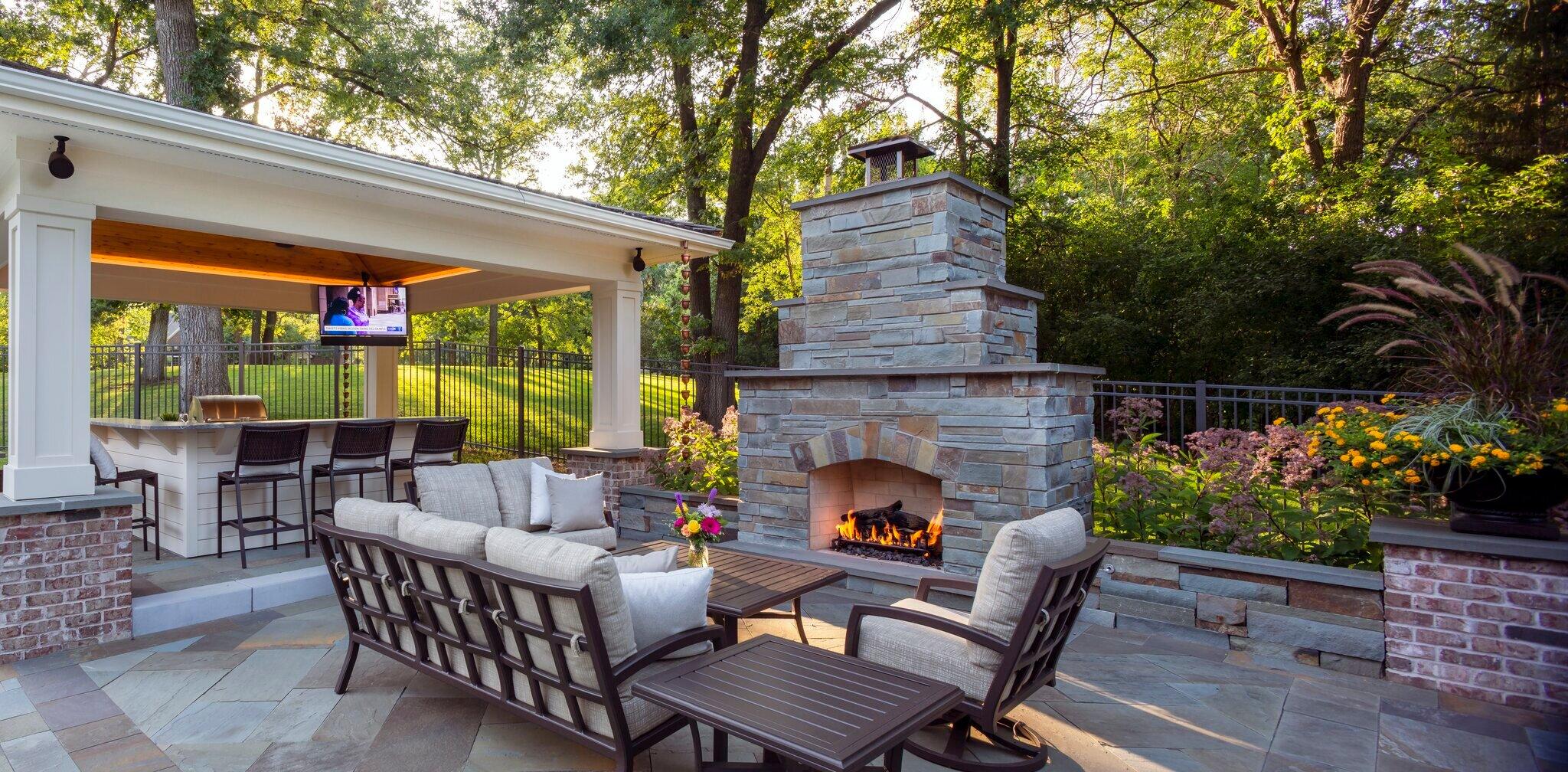 outdoor living room on bluestone patio featuring a gas fireplace and covered kitchen