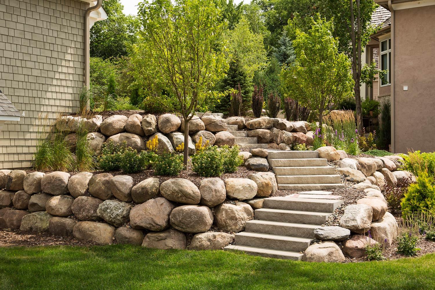 Boulder retaining wall with gardens and staircase
