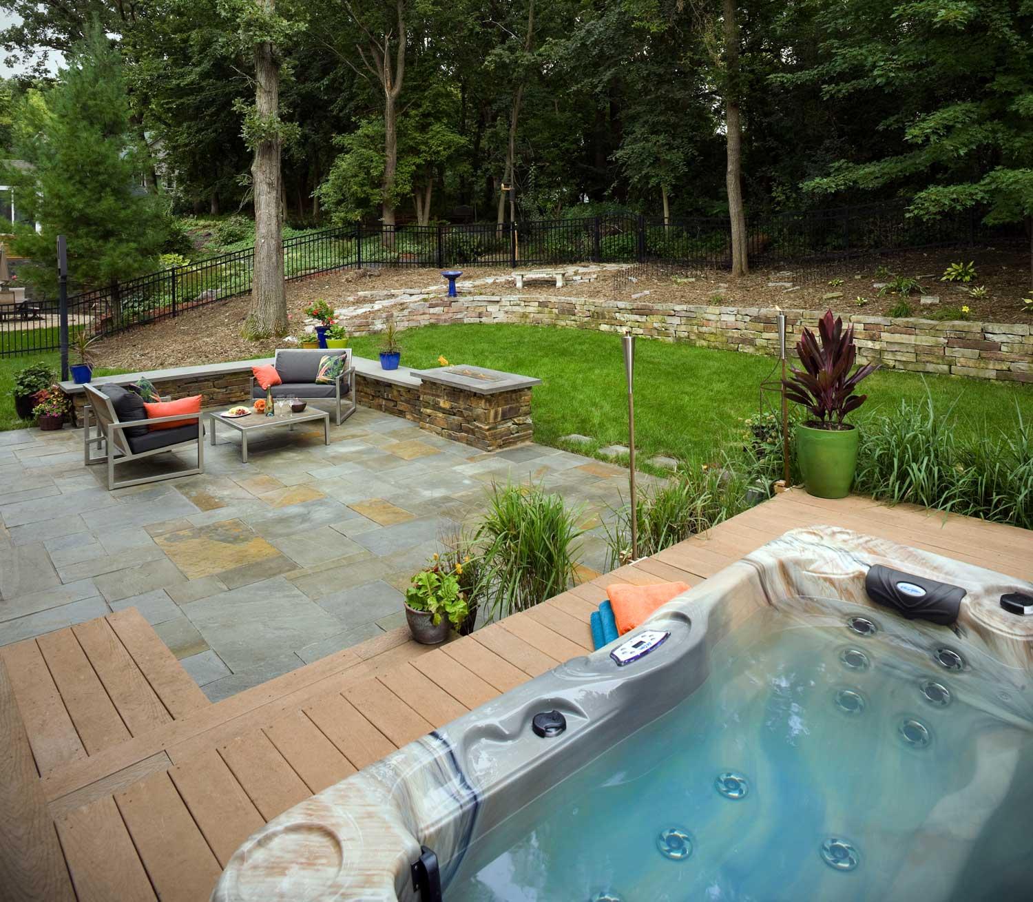 Hot tub deck and bluestone patio, stacked stone retaining wall, and modern outdoor fireplace