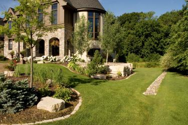Luxury backyard landscape design with gardens and sloped grade leading to a dry creek bed for drainage.