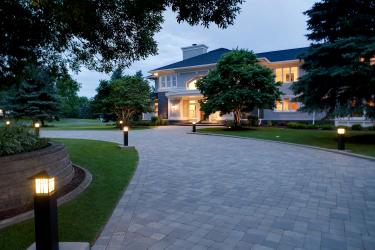 Elegant curving paver driveway flanked by tower lights