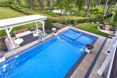 Custom fiberglass swimming pool in a backyard overlooking a natural wetland.