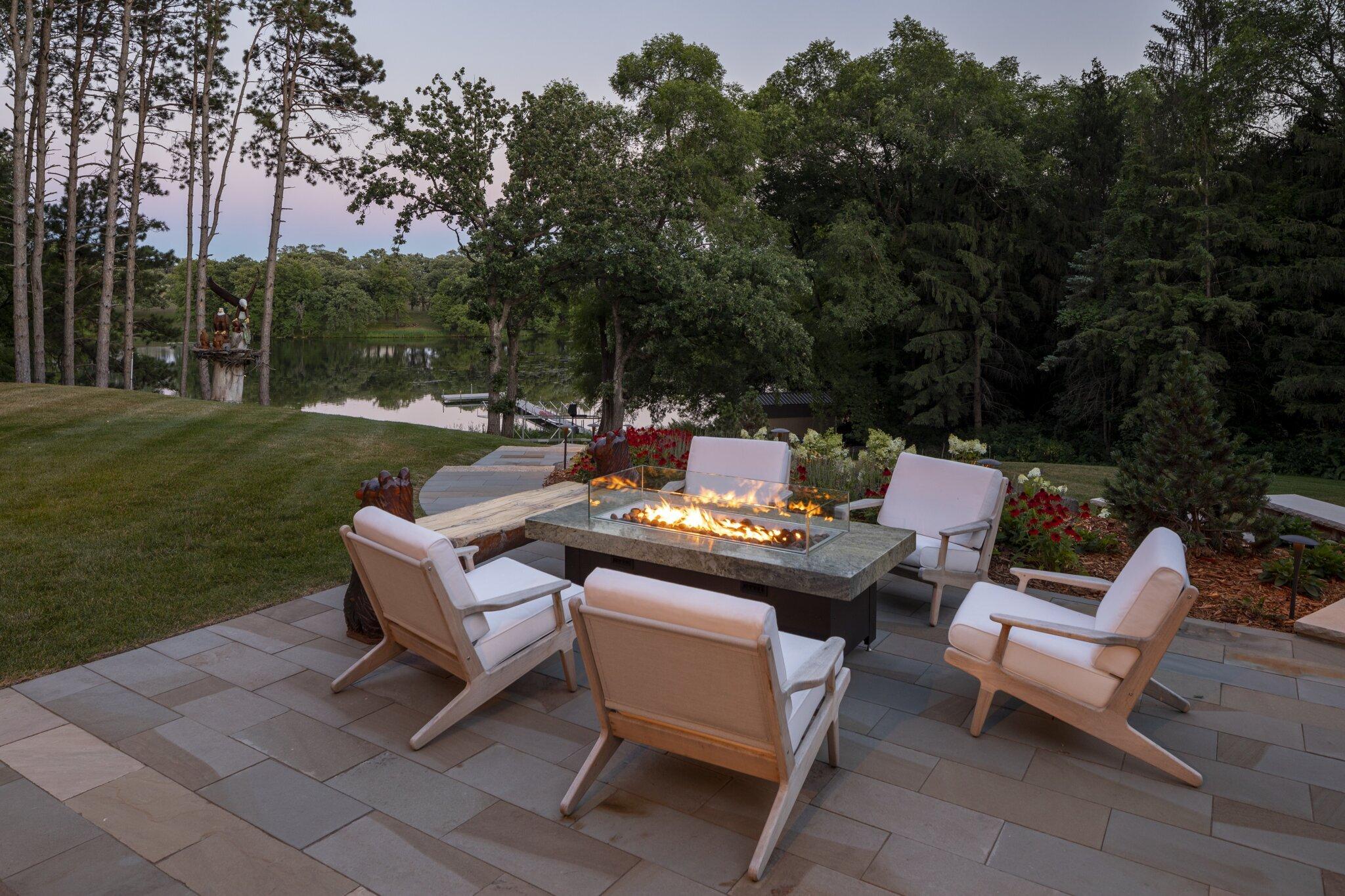 fire table on a bluestone patio overlooking a lake