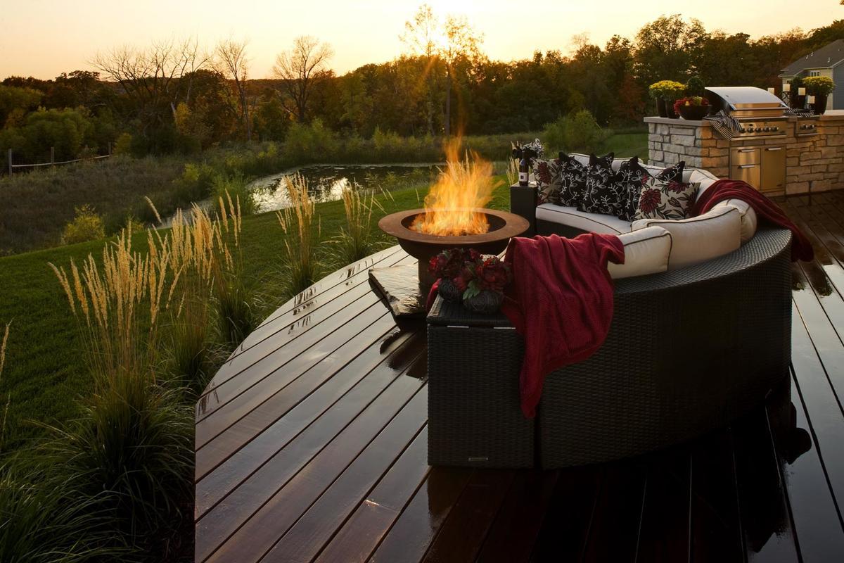 dark wood deck with a fire bowl over looking a woodland pond