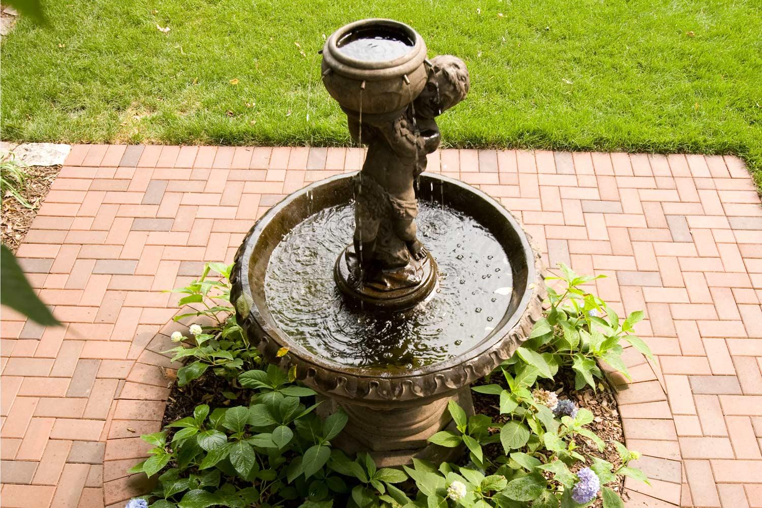 Sculptural water fountain feature and brick patio.