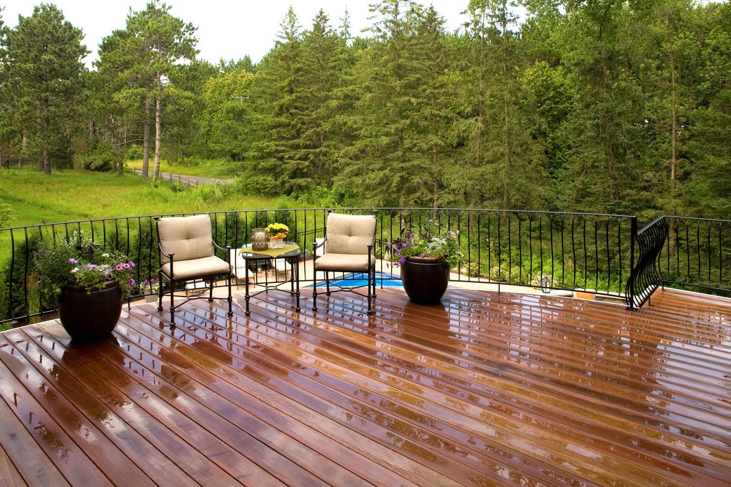 Elevated porch deck overlooks a pine forest and backyard swimming pool