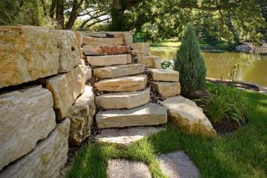 Stacked boulder retaining wall with stone staircase.