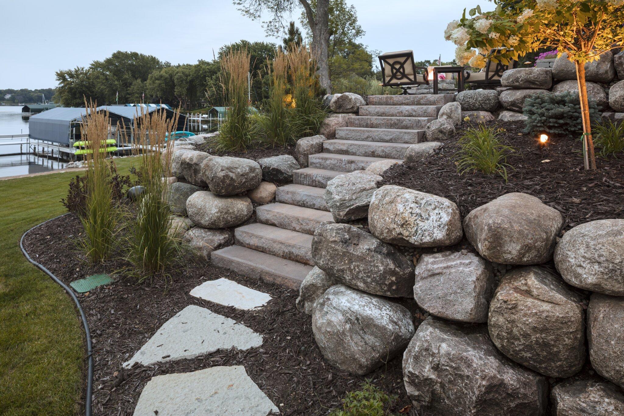 boulder wall with stone steppers, grasses and brown mulch