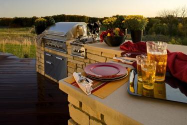 Outdoor kitchen with a woodland view at sunset.