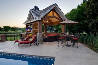 timber frame pool house structure and outdoor living room by a swimming pool