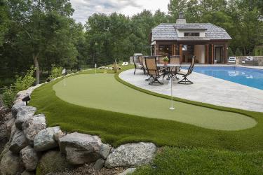 backyard putting green with swimming pool and pool house