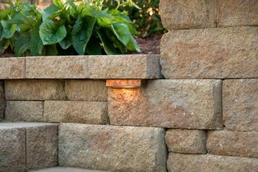 Modular block retaining wall with naturalistic texturing and integrated lighting.