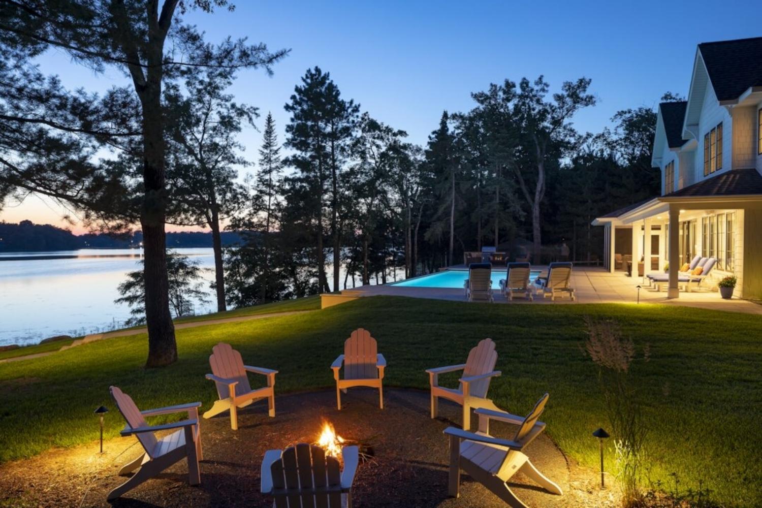 Sun setting on lake house with swimming pool, fire pit