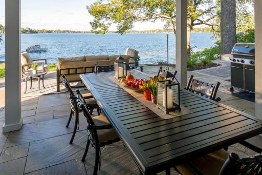 natural stone dining patio under deck overlooking a lake
