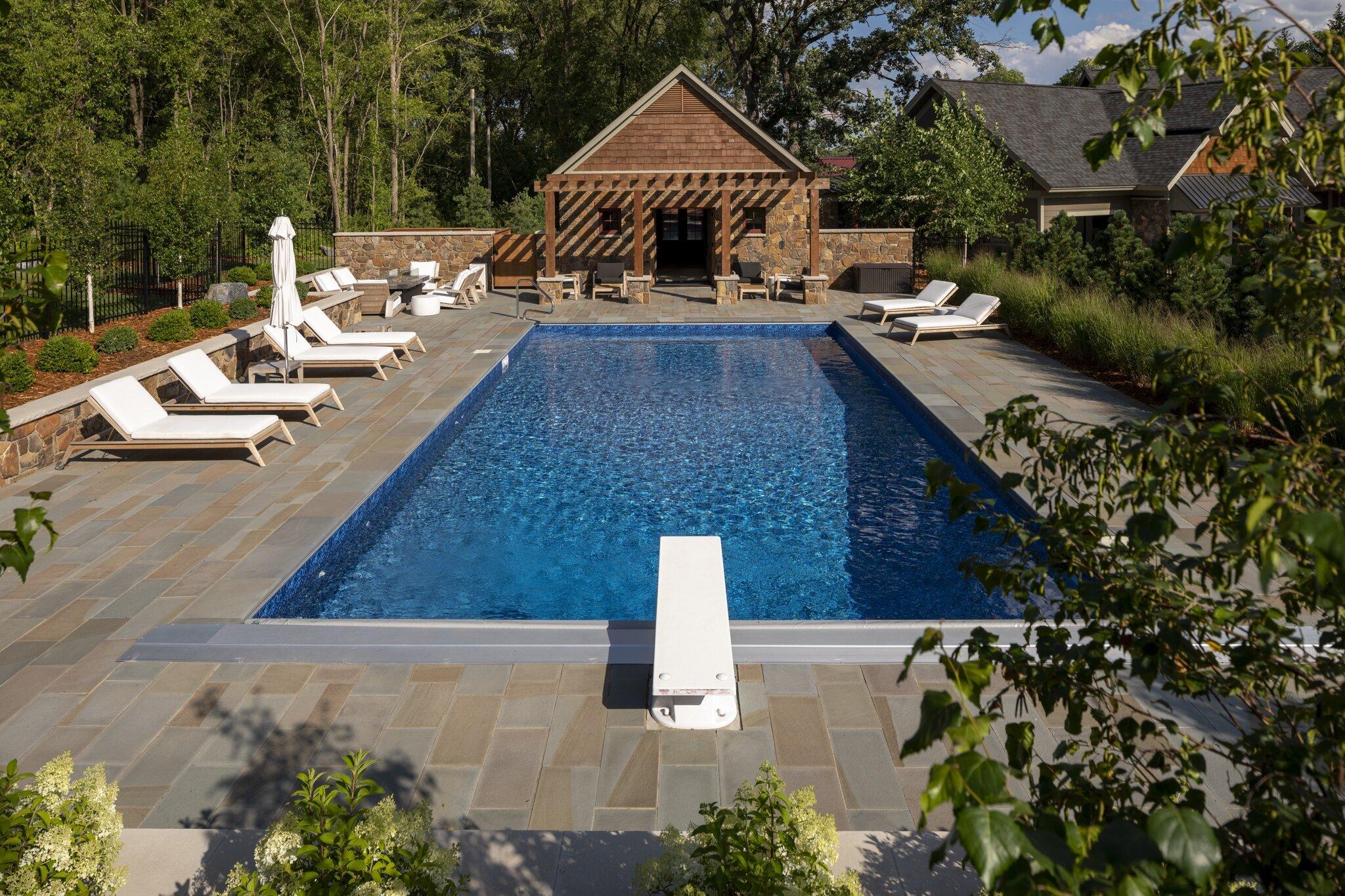 swimming pool with bluestone pool deck diving board and pool house